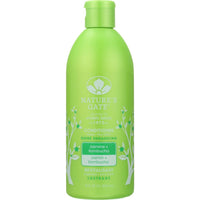 A bottle of Nature's Gate Jasmine + Kombucha Shine Enhancing Conditioner with a background of blooming jasmine flowers.